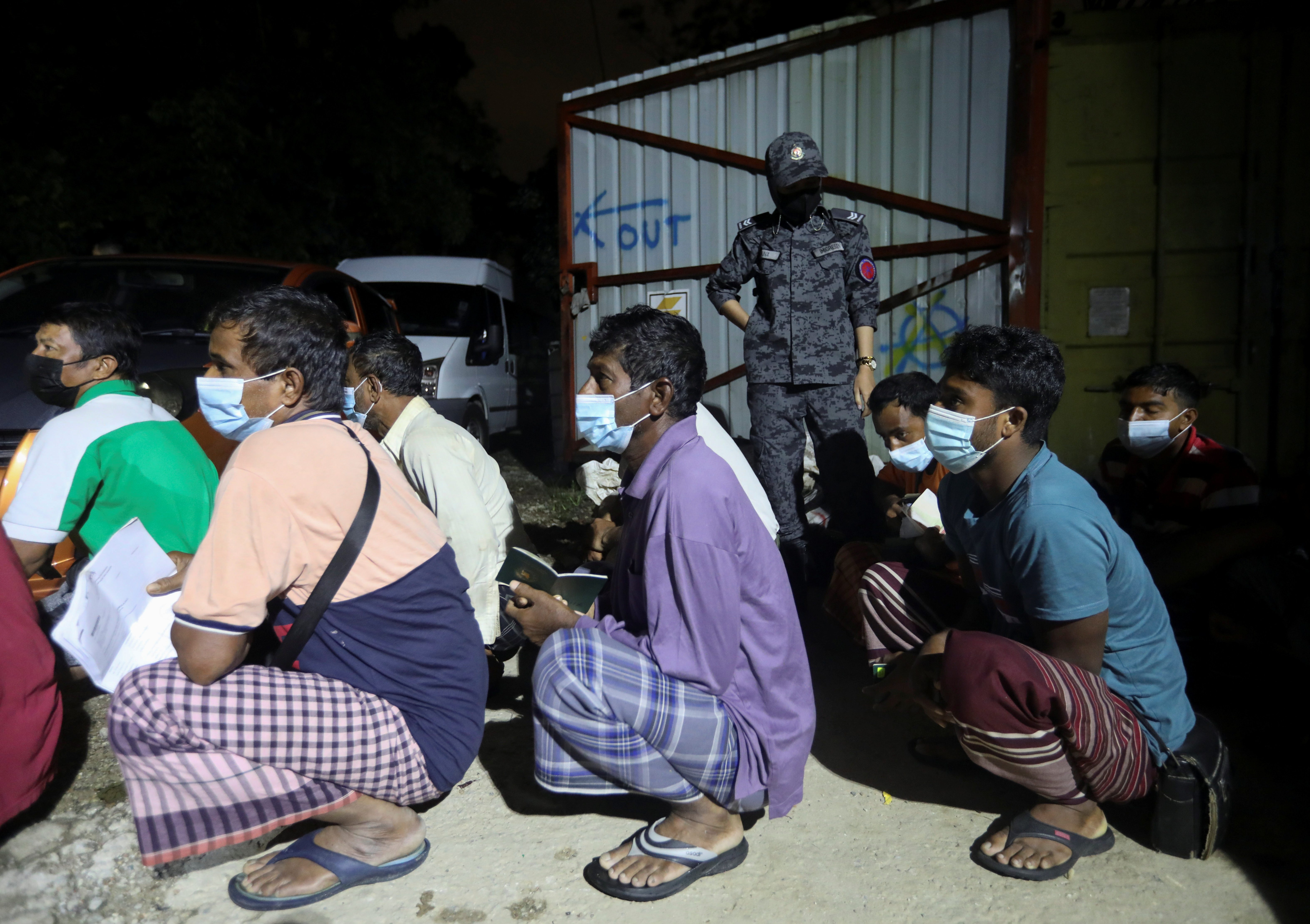 Bangladeshi migrant workers wait for their turn to have their documents checked in Kuala Lumpur