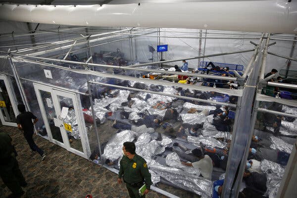 Children packed tightly inside a detention area, lying down on mats and under foil blankets.