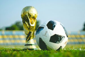 soccer ball and world cup trophy on soccer pitch