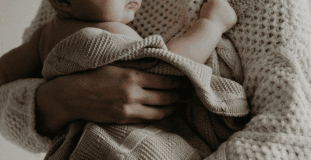 women holding baby in blanket